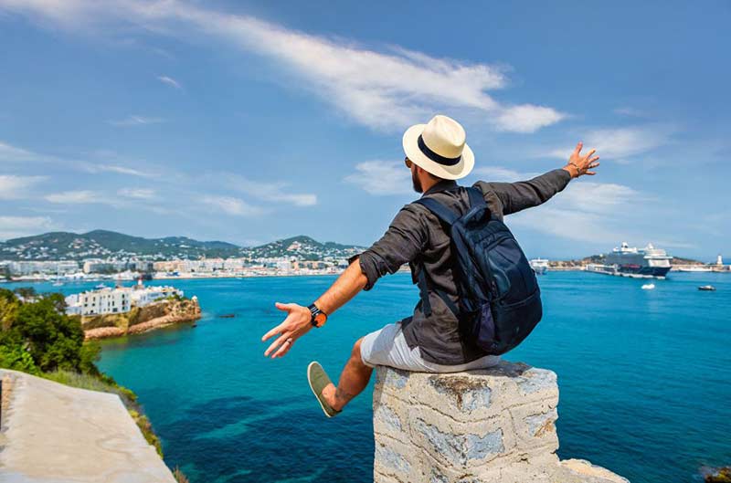 man sitting on a column by the beach